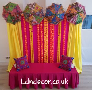 Colourful mehndi backdrip with garlands and umbrellas